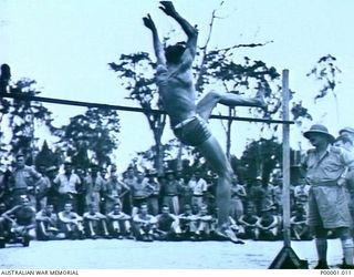 THE SOLOMON ISLANDS, 1945-01-12. A COMPETITOR RETURNING TO EARTH AFTER CLEARING THE BAR DURING THE HIGH JUMP AT A COMBINED ANZAC SPORTS MEETING AT BOUGAINVILLE ISLAND. (RNZAF OFFICIAL PHOTOGRAPH.)