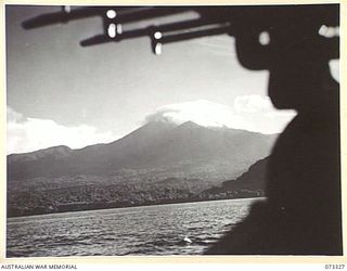 KARKAR ISLAND, NEW GUINEA. 1944-05-18. THE ISLAND, FRAMED BY MACHINE GUNS ABOARD HMA MOTOR LAUNCH 806, AND VIEWED FROM A RANGE OF APPROXIMATELY 500 YARDS. THE 5,000 FOOT VOLCANIC PEAK IS USUALLY ..