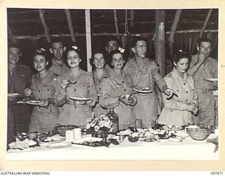 LAE, NEW GUINEA. 1945-09-24. A GROUP OF AUSTRALIAN ARMY MEDICAL WOMEN'S SERVICE AND THEIR FRIENDS AT THE BUFFET SUPPER TABLE. A BUFFET DINNER AND DANCE WAS HELD BY QUEENSLAND AUSTRALIAN ARMY ..