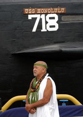 Brother Franklin Pao stands next to the sail of the Los Angeles Class Attack Submarine USS HONOLULU (SSN 718) before performing the Hawaiian water blessing during a farewell ceremony, at Pearl Harbor, Hawaii (HI)