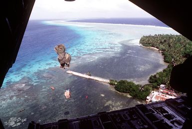 Boxes rigged with parachutes drift toward the water after being dropped from a 374th Airlift Squadron C-130 HErcules aircraft during the delivery of boxes of gifts to islanders of the Federated States of Micronesia. Flown by crews from the 345th and the 21st Airlift Squadrons, the C-130 is participating in Christmas Drop '92, the 40th anniversary of the humanitarian effort. Every Christmas since 1952, food, clothing, tools and toys donated by residents of Guam have been delivered by air to 40 Micronesian islands