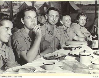 1942-11-23. UNITED STATES NURSES IN NEW GUINEA. LUNCH TIME IN THE MEDICO'S MESS SOMEWHERE IN NEW GUINEA. FROM LEFT TO RIGHT:- JEAN WEBSTER OF WEYMOUTH, MASS; JUNITA HAMILTON OF HENDERSONVILLE, N.C; ..