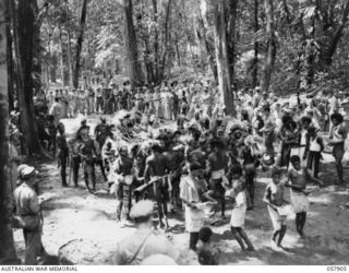 DOBODURA, NEW GUINEA. 1943-10-10. NATIVE CEREMONIAL DANCES IN PROGRESS IN THE VILLAGE CLEARING WERE ATTENDED BY ALLIED TROOPS AND NURSES