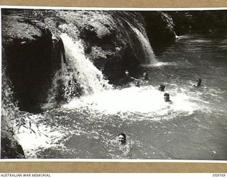FINSCHHAFEN AREA, NEW GUINEA, 1943-10-25. TROOPS OF THE 9TH AUSTRALIAN DIVISION SWIMMING BELOW THE FALLS ON THE MAPE RIVER NEAR THE TIMBULUM SAW MILL