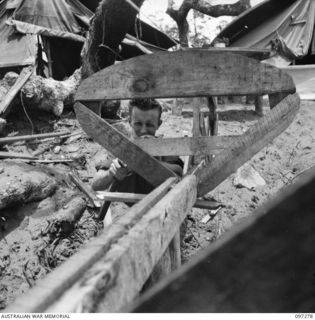 CAPE PUS, NEW GUINEA. 1945-09-29. PRIVATE W.J. KEENAN, 2/3 INFANTRY BATTALION, TRYING HIS HAND AT BOAT BUILDING