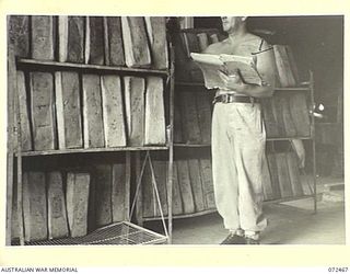 PORT MORESBY, NEW GUINEA. 1944-04-20. NX164506 CORPORAL G. DICKINSON, 6TH FIELD BAKING PLATOON, CHECKING THE NUMBER OF LOAVES ON COOLING RACKS AFTER THEIR REMOVAL FROM OVENS AT THE UNIT BAKERY