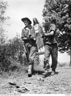 ALEXISHAFEN, NEW GUINEA, 1944-05-18. TX379 LIEUTENANT E.W.J. BRANAGAN (LEFT), AND Q268852 PRIVATE R.N. MULLER (RIGHT), MEMBERS OF THE 35TH INFANTRY BATTALION, CARRYING THE STATUETTE OF JESUS CHRIST ..