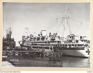 LAE, NEW GUINEA. 1945-06-09. PATIENTS OF 2/7 GENERAL HOSPITAL BEING UNLOADED FROM AMBULANCES AT MILFORD HAVEN WHARF FOR EMBARKATION ON THE HOSPITAL SHIP MANUNDA