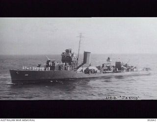1942-02-26. AERIAL PORT SIDE VIEW OF THE DESTROYER USS JARVIS (DD-393). THE AFTER 5 INCH/38 GUNS HAVE BEEN LEFT UNSHIELDED AS A WEIGHT SAVING MEASURE. THE TRUNKING OF THE BOILER UPTAKES INTO A ..