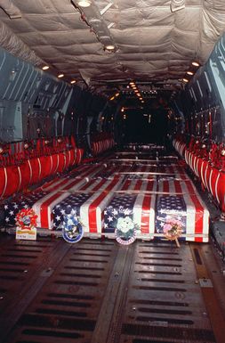 Boxes containing the remains of MIAs from Southeast Asia, covered with wreaths and American flags, wait inside a C-141B Starlifter aircraft for the repatriation ceremony at the Military Airlift Command terminal
