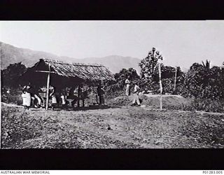 SALAMAUA, NEW GUINEA, 1940-04-?. THE SALAMAUA PLATOON OF THE NEW GUINEA VOLUNTEER RIFLES (NGVR) AT THE RIFLE RANGE, WATCHED BY NATIVES UNDER A SHADE SHED. (DONOR H. WALTER)