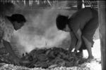 Packing the fire in the galafu (fire pit) with coconut husks prior to piling on the coral cooking surface