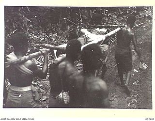BOUGAINVILLE. 1945-05-20. NATIVE CARRIERS TRANSPORTING A 58/59 INFANTRY BATTALION BATTLE CASUALTY BACK TO THE ADVANCED DRESSING STATION DURING THE DRIVE AGAINST THE JAPANESE IN SOUTH BOUGAINVILLE