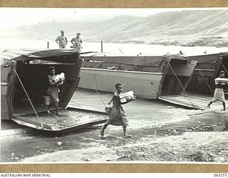 WALINGAI BEACH, NEW GUINEA. 1944-01-02. NATIVES CARRYING BREAD ASHORE FROM UNITED STATES NAVY BARGES