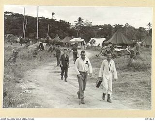 MADANG, NEW GUINEA. 1944-05-18. THE 111TH CASUALTY CLEARING STATION. NX11529 LIEUTENANT R.A. DICKSON, 8TH FIELD COMPANY (2), WALKS ALONG THE ROAD