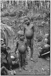 Smoking woman with netbag of firewood, two children