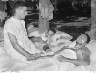 1943-05-07. NEW GUINEA. MILNE BAY. AN ALLIED VESSEL WAS HIT DURING THE 1943-04-14, JAPANESE RAID ON MILNE BAY. PICTURE SHOWS SGT. I.A. STRINGER OF NUMURKAH, VIC, WITH TWO WOUNDED MEMBERS OF THE ..