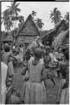 Mortuary ceremony: woman holds banana leaf bundles (wealth items) aloft during exchange