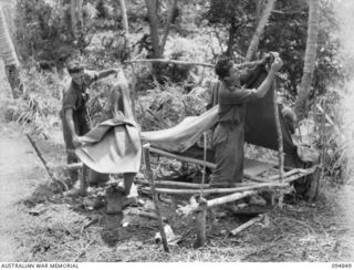 ILIPEM, NEW GUINEA, 1945-07-31. PRIVATE K.J. FRAZER (1), AND PRIVATE C.V. DOOLAN (2), MEMBERS OF 2/5TH INFANTRY BATTALION, BREAKING CAMP DURING PREPARATIONS FOR THE BIG MOVE FORWARD TO CRACK ..
