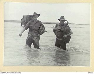 DANMAP RIVER, NEW GUINEA. 1945-01-06. NX128780 CAPTAIN J.S. JEFFREYS, HEADQUARTERS, 16TH INFANTRY BRIGADE AND A FELLOW OFFICER WADING ACROSS THE FLOODED RIVER