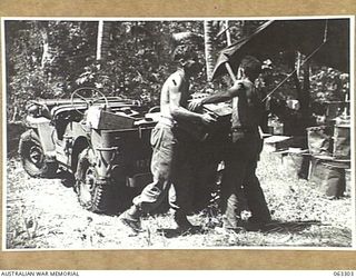 KANOMI BEACH, NEW GUINEA. 1944-01-04. NX29502 CORPORAL R. D. CONSON (1) AND QX14190 PRIVATE F. C. ANGUS (2) OF HEADQUARTERS 9TH DIVISION UNLOADING RATIONS AT THE UNIT KITCHEN