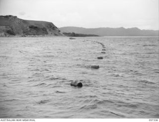 BOERA POINT, NEW GUINEA. 1943-10-01. DRUMS WITH THE MARINE CABLE ATTACHED BEING TOWED FROM THE SS MERNOO TO THE SHORE