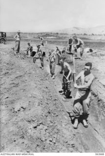 DUMPU, NEW GUINEA. 1943-12-21. PERSONNEL OF NO. 4 PLATOON, 2/5TH AUSTRALIAN FIELD COMPANY, ROYAL AUSTRALIAN ENGINEERS ENLARGING A DRAIN NEAR THE DUMPU AIRSTRIP. SHOWN ARE: NX91285 SAPPER W. SHUTT ..