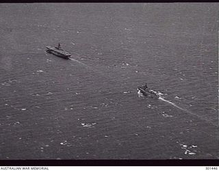 1949-09. AERIAL PORT QUARTER VIEW OF THE AIRCRAFT CARRIER HMAS SYDNEY (III) AND THE DESTROYER HMAS WARRAMUNGA IN COMPANY EN ROUTE TO MANUS. (NAVAL HISTORICAL COLLECTION)