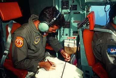 STAFF SGT. James Huber, flight engineer with the 21st Tactical Airlift Squadron, records data from the cockpit of a C-130 Hercules aircraft during a Christmas Drop mission. The annual airdrop is a humanitarian effort providing aid to needy islanders throughout Micronesia during the holiday season