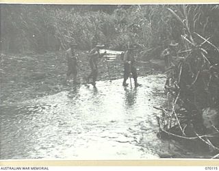 KETOBA, NEW GUINEA. 1944-01-29. MEMBERS OF THE 57/60TH INFANTRY BATTALION CROSSING A STREAM BEFORE MOVING INTO ACTION AGAINST THE JAPANESE