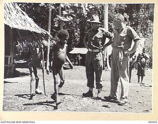 SIPILANGAN, NEW BRITAIN, 1945-07-27. LIEUTENANT J.G. KINSEY (1) AND WARRANT OFFICER 2 T. PALFRAMAN (2), OBSERVING TWO NATIVE REFUGEE CHILDREN AT THE AUSTRALIAN NEW GUINEA ADMINISTRATIVE UNIT ..