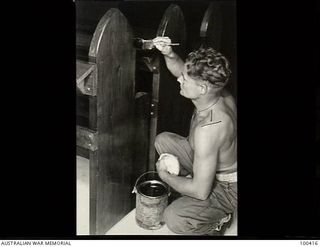 Port Moresby, New Guinea. 1944-05-13. Sapper P. Harrison, 10 Anti-aircraft and Fortress Company, Royal Australian Engineers, staining one of the pews built by members of the unit in their spare ..