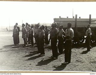 NEWCASTLE, NSW. 1944-01-28. AUSTRALIAN AND NEW GUINEA ADMINISTRATION UNIT (ANGAU) NATIVES WATCHING A MAGNETIC CRANE GRAB IN OPERATION AT THE STEEL MILLS OF BROKEN HILL PTY LTD