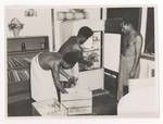 Three men filling a refrigerator, Port Moresby, c1947