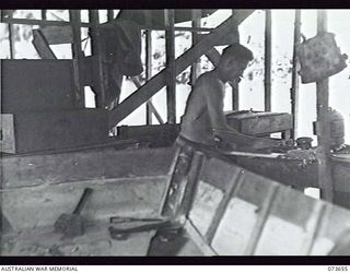 SALAMAUA, NEW GUINEA. 1944-06-01. N298417 PRIVATE R. FERNANCE, 2ND MARINE FOOD SUPPLY PLATOON, PLANING A STRUT WHICH WILL BE USED AS AN UPRIGHT IN A DINGHY UNDER REPAIR AT THE BOATSHED