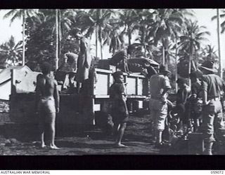 LAE, NEW GUINEA. 1943-10-17. NATIVES LOADING AN AUSTRALIAN AND NEW GUINEA ADMINISTRATION UNIT TRUCK WITH THE PROVISIONS REQUIRED ON A NATIVE RECRUITING MISSION TO THE BUKAUA AND HOPOI AREAS