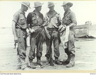 HANSA BAY, NEW GUINEA. 1944-06-22. MEMBERS OF THE 4TH INFANTRY BATTALION ADMIRING A CAPTURED JAPANESE SAMURAI SWORD. THEY ARE:- Q106990 PRIVATE N.F. SHILLING; NX86826 PRIVATE J.J. MAHONEY; NX120995 ..