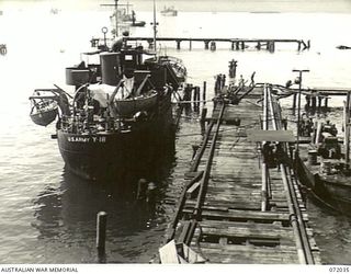 MILNE BAY, NEW GUINEA. 1944-04-05. THE UNITED STATES ARMY COASTAL TANKER Y - 18 VIEWED FROM A PILE DRIVER ON THE OIL WHARF AFTER RECEIVING AVIATION FUEL FROM SHORE INSTALLATIONS AT THE 2ND ..