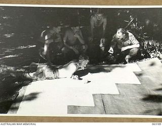 KILIGIA BEACH, NEW GUINEA. 1943-12-28. MEMBERS OF THE INTELLIGENCE SECTION, HEADQUARTERS 9TH DIVISION ASSEMBLING A LARGE MAP OF THE KILIGIA BEACH AREA. SHOWN ARE: QX27726 CORPORAL C. MCNAUGHT (1); ..