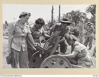 LAE, NEW GUINEA, 1945-05-18. PERSONNEL FROM AUSTRALIAN WOMEN'S ARMY SERVICE BARRACKS EXAMINING CAPTURED JAPANESE GUN AT THE BASE OF MOUNT LUNAMAN. THEY ARE TAKING PART IN A TOUR OF THE AREA ..