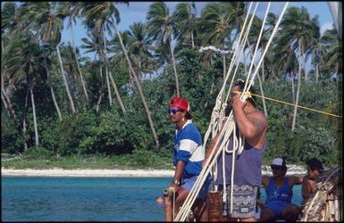 Two men in blue tops standing on boat