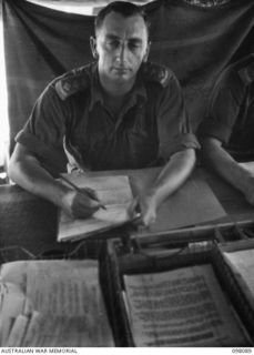 CAPE WOM, NEW GUINEA. 1945-10-17. CAPTAIN W.F. ROBESON, OFFICER- IN- CHARGE DEMOBILIZATION HEADQUARTERS 6 DIVISION AT WORK IN HIS OFFICE