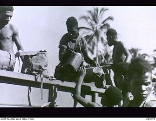 LAE, NEW GUINEA. 1943-10-17. NATIVES LOADING AN AUSTRALIAN AND NEW GUINEA ADMINISTRATION UNIT TRUCK WITH THE PROVISIONS REQUIRED ON A NATIVE RECRUITING MISSION TO THE BUKAUA AND HOPOI AREAS