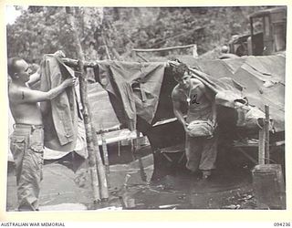 SOUTH BOUGAINVILLE. 1945-07-21. PRIVATE L.N. DENNIS (1) AND PRIVATE C. ROBERTSON (2), MEMBERS OF 58/59 INFANTRY BATTALION, SALVAGING GEAR FROM THEIR FLOODED TWO-MAN TENT AT A COMPANY POSITION WEST ..