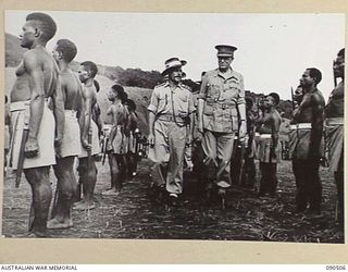 NEAR NADZAB, NEW GUINEA. 1945-03-26. LORD WAKEHURST, GOVERNOR OF NEW SOUTH WALES (2), ACCOMPANIED BY CAPTAIN A.I. GAY, OFFICER COMMANDING B COMPANY, 2 NEW GUINEA INFANTRY BATTALION (1), INSPECTING ..