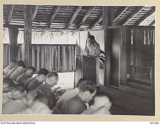 LAE, NEW GUINEA, 1945-05-09. CHAPLAIN E.M. WATTS ADDRESSING THE CONGREGATION AT 112 CONVALESCENT DEPOT DURING A THANKSGIVING SERVICE TO MARK THE END OF HOSTILITIES IN EUROPE