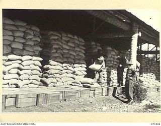 LAE, NEW GUINEA. 1944-03-29. MEMBERS OF THE 39TH SUPPLY DEPOT COMPANY ENGAGED IN STACKING 18,000 BAGS OF RICE UNDER THE SUPERVISION OF VX31344 WARRANT OFFICER CLASS 2 A. G. STRACHAN (4). THE BULK ..