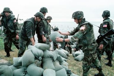 Marines pile up sandbags that are being filled on the beach at the edge of the US Embassy compound. Marines of the 22nd Marine Expeditionary Unit (22nd MEU), deployed aboard the amphibious assault ship USS SAIPAN (LHA 2), were sent to augment security at the embassy as part of Operation SHARP EDGE