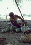 Young man pouring green coconut liquid into pot at his father's sister's cookhouse