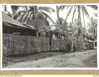 MILNE BAY, NEW GUINEA. 1943-06-29. NO. 1 GANG HUTS OF THE 2/3RD AUSTRALIAN DOCKS OPERATING COMPANY, ROYAL AUSTRALIAN ENGINEERS, AIF THE GANG IS SEEN RECEIVING INSTRUCTIONS FOR THE DAY'S WORK FROM ..